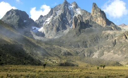 Trekkers ascending Mount Kenya on the Naro Moru Route, surrounded by alpine vegetation and dramatic peaks during a 5-day guided expedition.